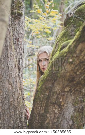 Blond long-haired girl in a fantasy black dress in an autumn forest scary halloween fairy tale