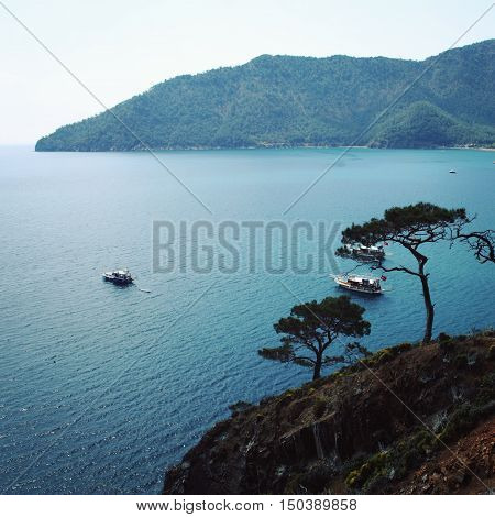Tourist boats in the sea. View on Adrasan Bay. Aged photo. Pine trees and sea. Toned image. Walking the Turkey's Lycian Way. Antalya Province Turkey.