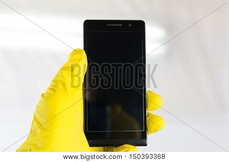 Hand in yellow gloves holding infected smartphone on white background. Information security concept