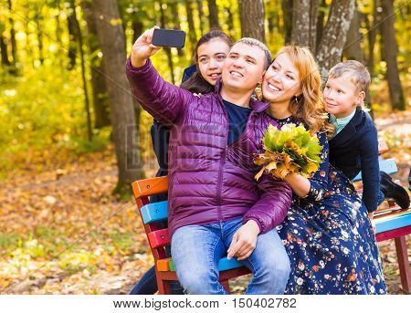 family, pet, season, technology and people concept - happy family with labrador retriever dog taking selfie by smartphone in autumnl park