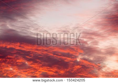 Romantic and dramatic cloud formation on dusk sky. Red and black warm landscape with sunlight.