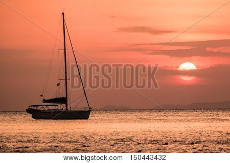 Scenic view of a sailing boat and beautiful sunset over the sea