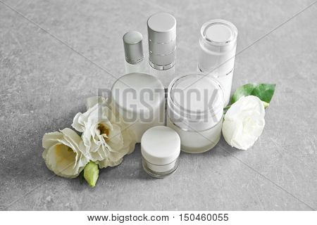 Cosmetic bottles and eustoma flowers on light wooden background