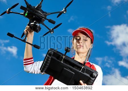 A woman is standing and holding drone
