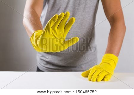 Young man in a yellow rubber gloves refuses to do housework, snowing 'no' sighn