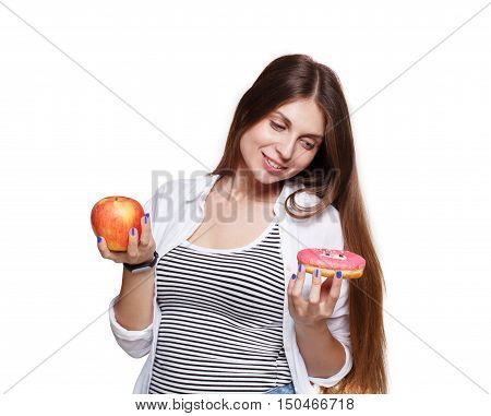 Choose healthy food, diet concept. Beautiful long-haired young woman with big ripe red apple in one hand and a donut in another. Female portrait isolated on white background.