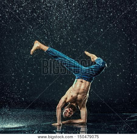 The male break dancer in water on dark background.