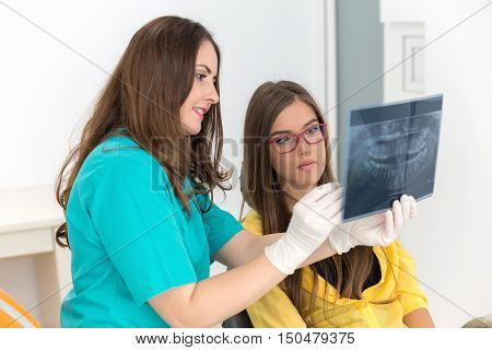 Female dentist showing her patient x-ray radiography, in the Dental Clinc