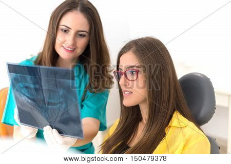 Female dentist showing her patient x-ray radiography, in the Dental Clinc