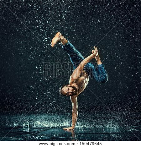 The male break dancer in water on dark background.