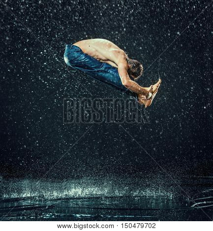 The male break dancer in water on dark background.