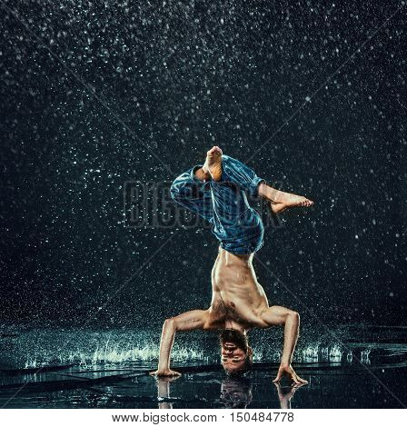 The male break dancer in water on dark background.