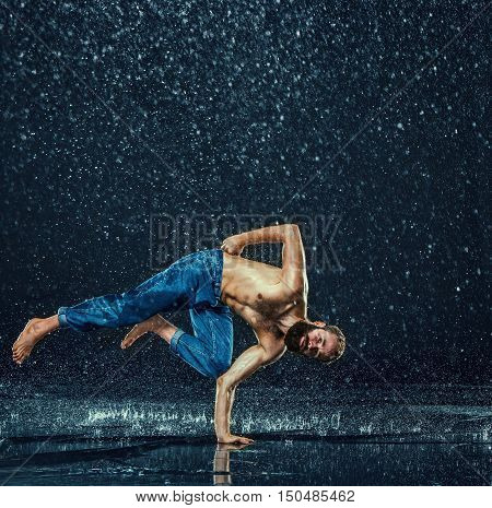 The male break dancer in water on dark background.