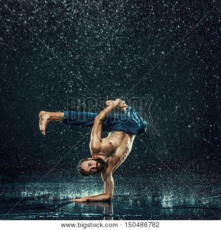 The male break dancer in water on dark background.