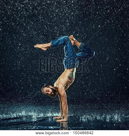 The male break dancer in water on dark background.