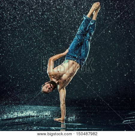 The male break dancer in water on dark background.