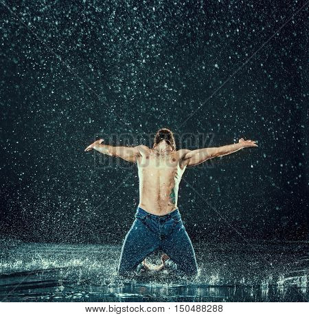 The male break dancer in water on dark background.