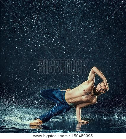 The male break dancer in water on dark background.