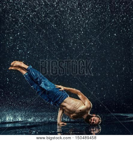 The male break dancer in water on dark background.