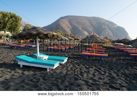 Tanning beds and umbrellas on Perissa beach Santorini Greece