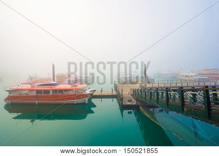 SUN MOON LAKETAIWAN - MARCH 21: Fog with many boats parking at the pier while sunrise on MARCH 21 2015 at Sun Moon Lake Taiwan. Sun Moon Lake is the largest body of water in Taiwan with nataral place.