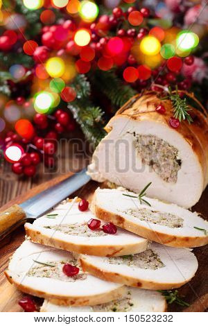 Stuffed turkey breast with pomegranate and rosemary on cutting board.