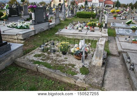 Graves tombstones and crucifixes on traditional cemetery. Votive candles lantern and flowers on tomb stones in graveyard. All Saints' Day. All Souls' Day. Gravestones in Slovak village