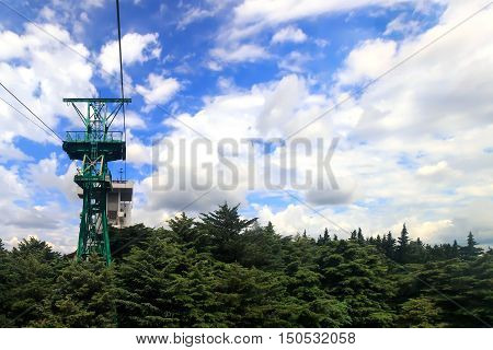 Cable car with a trailer over the picturesque arboretum in the resort town.