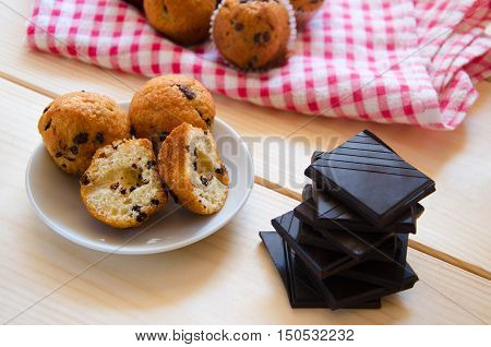 Cut little chocolate muffins on white plate with crushed chocolate on wooden background