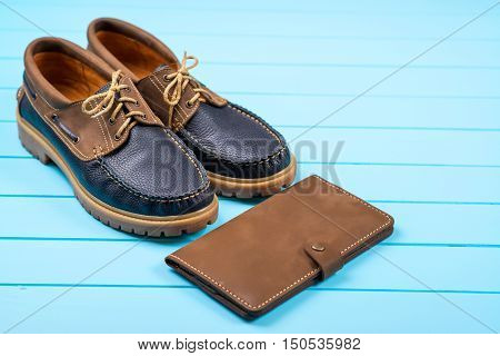 Men's accessories with a brown purse and shoes. Top view on wooden background.