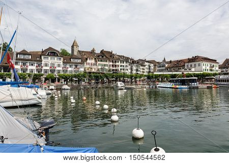 RAPPERSWIL SWITZERLAND - MAY 10 2016: Buildings of Rapperswil by the promenade that is planted with trees as seen from the lake.