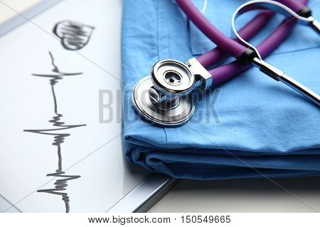 Doctor coat with stethoscope on the desk .
