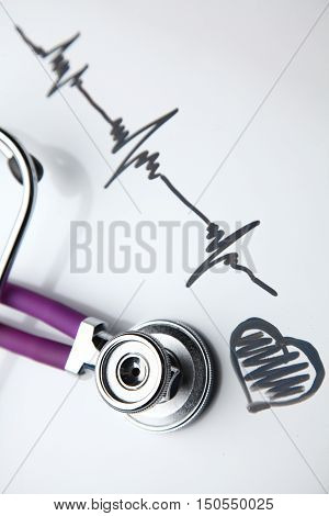 Stethoscope with cardiogram lying on desk in hospital