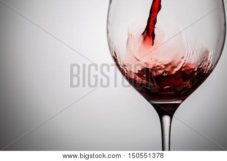 Pouring red wine into transparent glass. Image with copy space