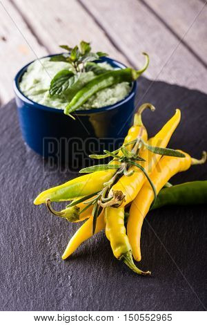 Bunch Of Yellow And Green Chili Pepers With Wasabi Dip In Blue Bowl