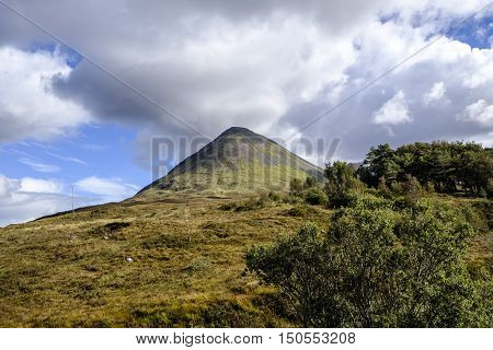 Looking across the beautiful landscape of isle of Skye Scotland to the sun shining on the conical shape of Glamaig in the Red Hills mountain range.