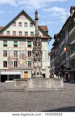 LUCERNE SWITZERLAND - MAY 10 2016: Weinmarkt Fountain that is 15th-century fountain and is surrounded by historical buildings decorated with frescos and it is located at the square in the old town