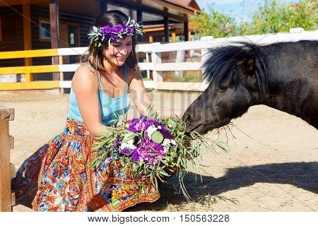 Beautiful girl feeding the straw pony on the farm.