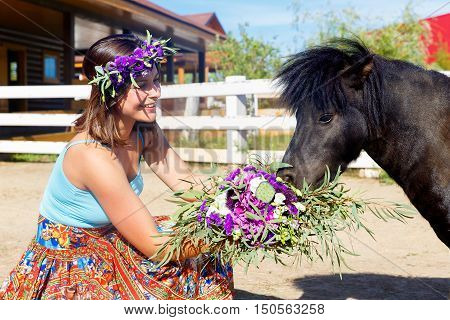Beautiful girl feeding the straw pony on the farm.