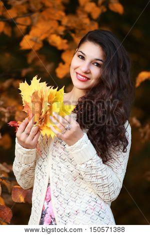 portrait of a beautiful girl with maple yellow leaves