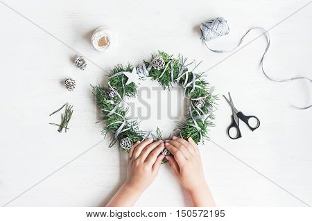 Christmas. Child making handmade christmas wreath. Top view flat lay