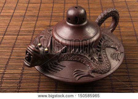 brown Chinese teapot of Yixing clay with traditional ornament on bamboo Mat