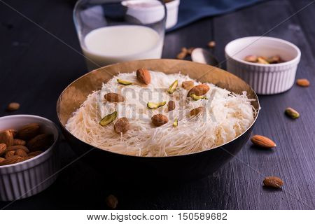 Indian sweet sutarfeni or sutar feni or firni or seviyan or laccha, shredded, flaky-rice-flour roasted in ghee, blended with melted sugar to form a cotton candy, topped with pistachio and almonds