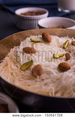 Indian sweet sutarfeni or sutar feni or firni or seviyan or laccha, shredded, flaky-rice-flour roasted in ghee, blended with melted sugar to form a cotton candy, topped with pistachio and almonds