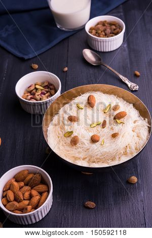 Indian sweet sutarfeni or sutar feni or firni or seviyan or laccha, shredded, flaky-rice-flour roasted in ghee, blended with melted sugar to form a cotton candy, topped with pistachio and almonds