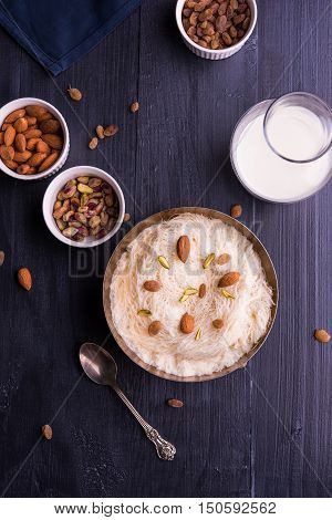 Indian sweet sutarfeni or sutar feni or firni or seviyan or laccha, shredded, flaky-rice-flour roasted in ghee, blended with melted sugar to form a cotton candy, topped with pistachio and almonds