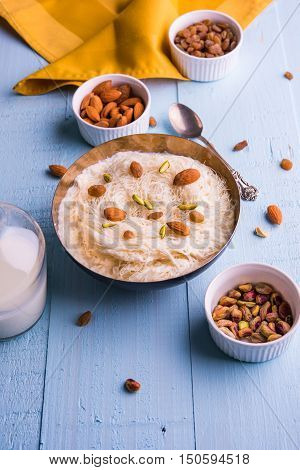 Indian sweet sutarfeni or sutar feni or firni or seviyan or laccha, shredded, flaky-rice-flour roasted in ghee, blended with melted sugar to form a cotton candy, topped with pistachio and almonds