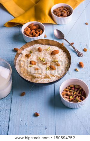 Indian sweet sutarfeni or sutar feni or firni or seviyan or laccha, shredded, flaky-rice-flour roasted in ghee, blended with melted sugar to form a cotton candy, topped with pistachio and almonds
