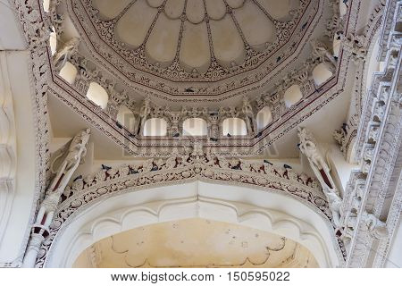 Madurai India - October 21 2013: Shot on the abundant decoration of one dome and the supporting columns and bow at Nayak Palace. White with wine-colored images. Pigeons.
