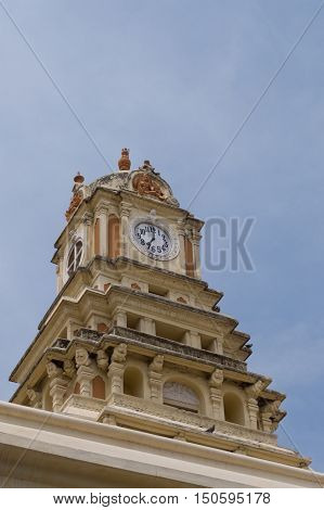 Madurai India - October 21 2013: The clock tower of the Nayak Palace against blue sky. Dials show seven o'clock.